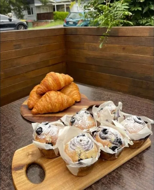 Croissants and blueberry muffins on timber boards out on the deck