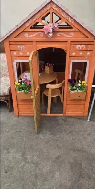 The timber cubby house at the cafe, with its little door open and a tiny table and chairs inside